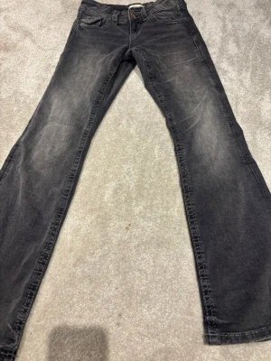 Svarta jeans med broderade fickor Gina Tricot - Snygga svarta jeans från Gina Tricot i storlek 152. Jeansen har bootcut-ben och coola broderade detaljer med paljetter på bakfickorna. Klassisk femficksmodell med knapp och dragkedja framtill. Perfekt för dig som gillar en stilren look med lite extra edge.