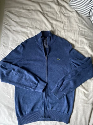 Lacoste zip - Fin kofta med full zip från Lacoste med klassiska krokodilen inbroderad på bröstet. Skicket är bra förutom en liten fläck vid kragen (syns på bilden) men inget som märkts vid användning. Kontakta mig om frågor!😊