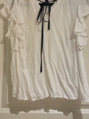 Vit volang blus  - Fin vit volang blus, som man kan knyta med en svart rosett till