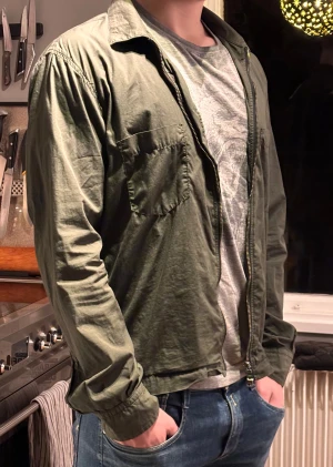 Grön overshirt från Oscar Jacobson - Säljer en stilren grön overshirt från Oscar Jacobson. Jackan har två bröstfickor, klassisk krage och dragkedja framtill. 