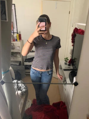 Randig croppad t-shirt🤍 - Säljer en fin croppad t-shirt med marinblå och vita ränder. T-shirten har korta ärmar och rund halsringning. Materialet är mjuk bomull som är skönt mot huden. Perfekt för dig som gillar en enkel och stilren look med lite edge.💞