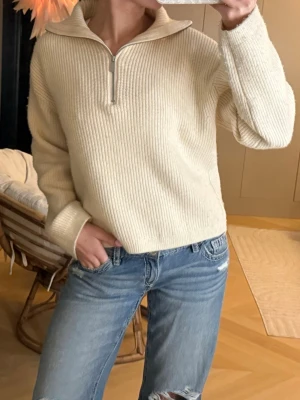 Beige stickad tröja med half zip - Säljer en beige stickad tröja med ribbad struktur och halv dragkedja framtill. Storlek XS från H&M 