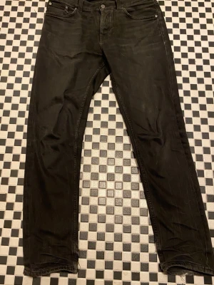 Svarta jeans från Nudie Jeans - Svarta jeans från Nudie Jeans med klassisk femficksdesign och raka ben. Jeansen har en diskret Nudie-logga på bakfickan och är tillverkade i slitstark bomull. Modellen steady Eddie II är versatil och passar många stilar!