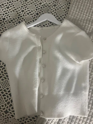 Söt vit kofta med knappar - Jättesöt kofta! Den är jätteskön och har inga större tecken på användning. Märke och storlek saknas men den är i bra skick!💕 passar xs-s/m skulle jag säga! Beror på vilken passform man vill ha.🥰