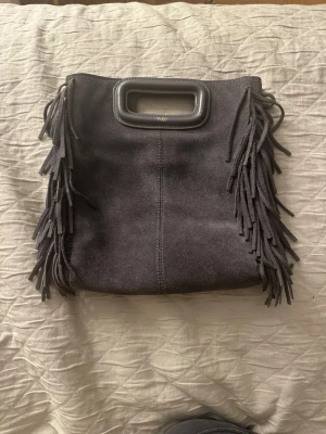 Maje väska - Mörkgrå maje väska i fint skick. Köpt för några år sedan så kvitto finns tyvärr inte kvar. Långt band medföljer, skriv för fler frågor