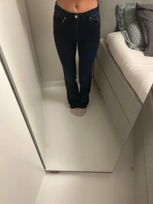 Mörkblå bootcut jeans - Snygga mörkblå jeans med bootcut-snitt och hög midja. Kan ha lite slitage då jag försökt sy ner de till lågmidjat med gett upp