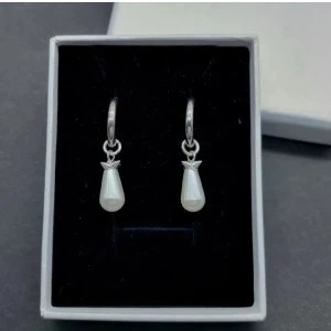 Silvriga örhängen med pärldroppe - Snygga örhängen i silverfärgad metall med hängande droppformad vit pärldetalj. Designen är stilren och modern med en liten metallkrona ovanför pärlan. Perfekt för dig som gillar minimalistiska smycken med en elegant touch.