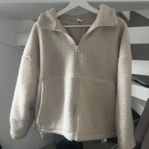 Beige teddyjacka från C.W.L i XS - Mysig beige teddyjacka från C.W.L i storlek XS. Jackan har dragkedja framtill, två stora fickor och snörning i nederkant för att justera passformen. Perfekt för kyliga dagar och riktigt skön att ha på sig. Bra skick och använd sparsamt. Storlek xs men skulle säga att den även passar s och m beroende på önskad passform 🫶🏼 Skriv vid fler frågor eller funderingar! (Pris kan även diskuteras vid snabb affär, köpt för 800 kr)