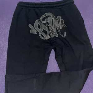 Svarta syna wrld byxor - Svarta mjukisbyxor från Syna Wrld. Perfekta för chill eller streetwear-stil. Hör av er vid funderingar!