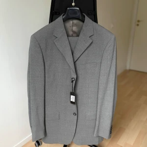 Ljusgrå kostym – Medi, Made in Italy (stl 48) - Stilren och modern kostym från italienska Medi. Ljusgrå färg som passar perfekt för vår, sommar och festliga tillfällen. Klassisk tvåknäppt modell med matchande byxor och helfodrad insida.  Storlek: 48  Färg: Ljusgrå  Märke: Medi – Made in Italy  Nypris: 3795 kr  Skick: Ny med tags