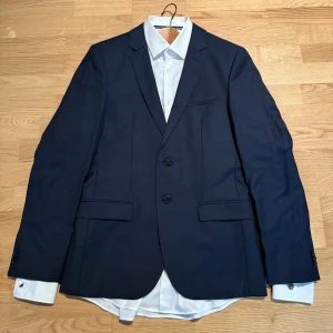 Hugo Arto kostym  - Säljer ett komplett Hugo Arti kostympaket: kavaj, byxor och skjorta – allt i mycket fint skick. Passar någon som normalt har M–L. Stilren och proffsig design som funkar både på jobbet och vid festliga tillfällen. Allt detta för endast 1450 kr!