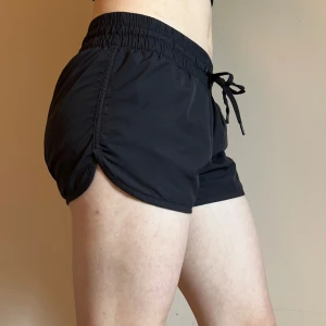 Svarta träningsshorts med snörning - Shorts med elastisk midja och snörning framtill. Modellen är kortare i benen