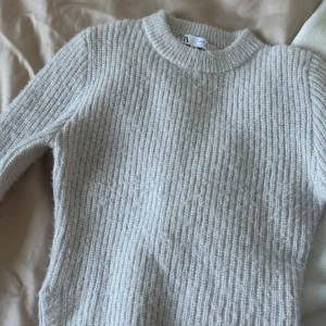 Ljusgrå stickad tröja från Zara - Supermjuk och mysig ljusgrå stickad tröja från Zara. Tröjan har en klassisk rund halsringning, ribbad struktur och långa ärmar. Som man ser på den andra bilden så är de en liten slits på vardera sida. Perfekt för lager-på-lager och chill höst- och vinterstil. Skriv gärna om du har frågor💕