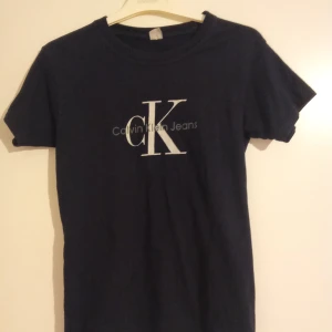 Svart t-shirt Calvin Klein Jeans Storlek S - Svart t-shirt från Calvin Klein Jeans med klassisk CK-logga i vitt på bröstet. Modellen är enkel med rund hals och korta ärmar. Materialet känns mjukt och skönt, perfekt till jeans eller shorts. Snygg och stilren design som funkar till många olika looks.