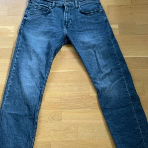 Blå jeans från Lee med raka ben - Säljer ett par klassiska blå jeans från Lee med raka ben och femficksdesign. Jeansen har normal passform och är tillverkade i slitstarkt denimtyg. Perfekta för dig som gillar en tidlös look och vill ha ett par jeans som funkar till allt. Storlek: W30 L32