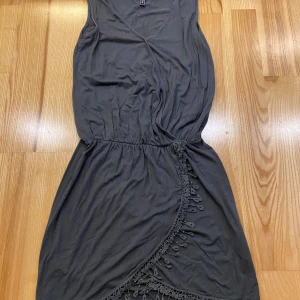 Rainbow grön klänning, storlek XS - Grön klänning från Rainbow med v-ringning och dekorativ spetskant nedtill. Klänningen har resår i midjan.