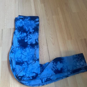 Blå tie-dye leggings - Säljer ett par blå leggings med coolt tie-dye mönster i olika blå nyanser. De är stretchiga och sitter tight, perfekta för dig som vill ha något bekvämt och snyggt till träning eller chill. Materialet känns mjukt mot huden och de har en hög midja.