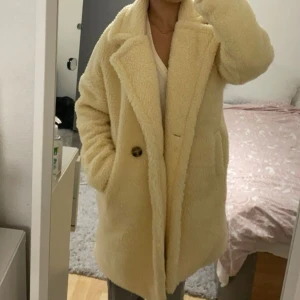 Beige teddykappa - Supermysig beige teddyjacka med oversized passform. Jackan har knäppning framtill med en knapp och två fickor på sidorna. Använd en gång, köpt för 600kr