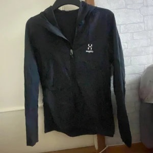 Svart jacka från Haglöfs med huva - Säljer en svart jacka från Haglöfs i storlek S. Jackan har huva, lång ärm och dragkedja framtill. Perfekt för dig som gillar en enkel och stilren look.