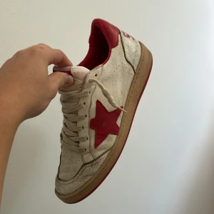 Golden Goose sneakers med röd stjärna - Golden Goose sneakers i beige med röd stjärndetalj på sidan och röd häl. Skorna har snörning, perforerade detaljer framtill och en röd sula med stjärnmönster undertill. Ovandelen är i skinn och mocka för en cool vintage vibe. Skorna har små diffekter på sulan (bild 2) inget märkvärdig men det är inräknat i priset självklar, allt og tillkommer!🍻