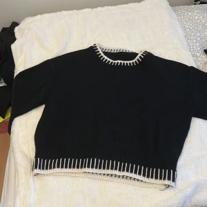 Svart stickad tröja från SHEIN XS - Svart stickad tröja från SHEIN i storlek XS. Tröjan har vita detaljer vid halsringning, ärmslut och nederkant som ger en snygg kontrast. Långärmad och med ribbade muddar för en chill och trendig look.