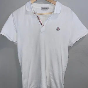 Vit Moncler pikétröja  - Vit pikétröja från Moncler | Storlek M Passar S | Bra skick förutom ett litet hål i nacken som syns på andra bilden | Hör gärna av dig vid frågor eller funderingar | Byten kan vara intressant | Pris kan diskuteras vid snabb affär✅✅