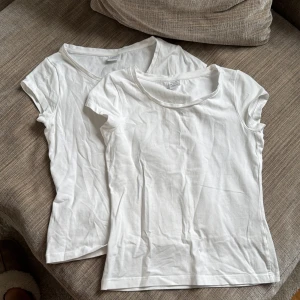 Vit t-shirt från Lindex 2-pack - Två vita t-shirts från lindex i storlek 146/152. Modellen är klassisk med rund hals och korta ärmar, tillverkad i en mjuk blandning av återvunnen och ekologisk bomull. Perfekt basic att ha i garderoben, enkel att matcha med allt.