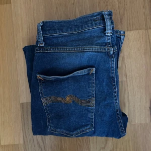 Mörkblå Grim Tim jeans från Nudie - Nudie jeans i modellen Grim Tim. Använda ett par gånger men inga synliga defekter. Skick 8/10.  Nypris är 1800kr, mitt pris 450kr. W31 L32. Vid frågor eller fundering skriv. 