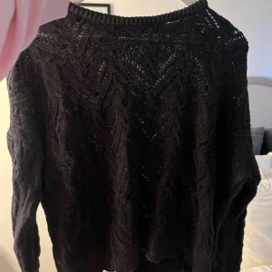 Svart stickad tröja med mönster - Mysig svart stickad tröja med snyggt strukturmönster och rund hals. Tröjan har långa ärmar och ribbade muddar vid hals, ärmslut och nederkant. Perfekt för lager-på-lager och passar till både jeans och kjol.