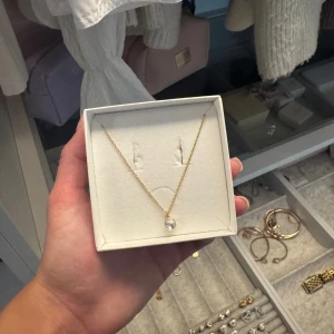 Guldhalsband med kristall från Caroline Svedbom - Supersnyggt halsband från Caroline Svedbom med tunn guldfärgad kedja och en glittrande rund kristall som hänger i mitten. Perfekt för att ge din outfit lite extra shine! Kommer i original ask. Helt nytt halsband