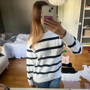 Randig vit och svart tröja från H&M - Säljer en vit tröja med svarta horisontella ränder från H&M. Tröjan har en klassisk rund halsringning och långa ärmar. Tillverkad i mjuk bomull, perfekt för en chill och stilren look. Passar dig som gillar enkel men snygg stil. Tröjan är i XS men som ni ser lite oversized.