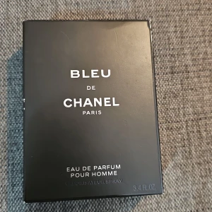 Bleu de Chanel Eau de Parfum 100ml - Bleu de Chanel Eau de Parfum Pour Homme, 100ml. Snygg svart rektangulär kartong med vit text och klassisk Chanel-design. En ikonisk herrdoft från Paris som levereras i originalförpackning. Perfekt för dig som gillar exklusiva och tidlösa parfymer.