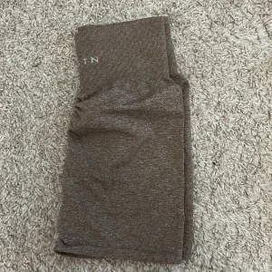 Bruna seamless shorts från NVGTN - Snygga bruna seamless shorts från NVGTN med hög midja och diskret scrunch-detalj bak. Stretchigt material som sitter tight och bekvämt, perfekt för gymmet eller andra träningspass. Stilren design med logga framtill i midjan.