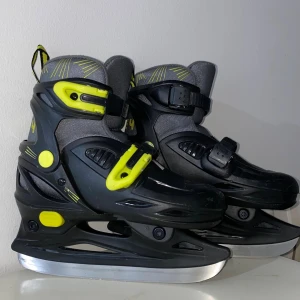 Rookie 4 svarta och grå skridskor - Snygga skridskor från Rookie 4 i svart och grått med coola gula detaljer. De har justerbara spännen och robust design som ger bra stöd runt foten. Perfekta för dig som vill sticka ut på isen med en sportig look och bekväm passform. Skidskor för barn med storken 29-32, och som ni ser på bilden är den helt nytt och har använts få gånger. Allt är som i bilden, meddela mig gärna om ni vill ha mer info! 💕