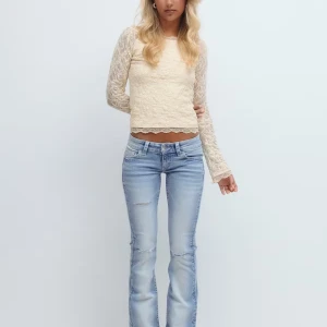 Bootcut jeans med broderad ficka - Snygga ljusblå bootcut jeans med slitningar och broderade detaljer med paljetter på bakfickan. Lågmidjade. En omsyd ficka och en bleknings fläck, se bilder! Där av pris och skick.
