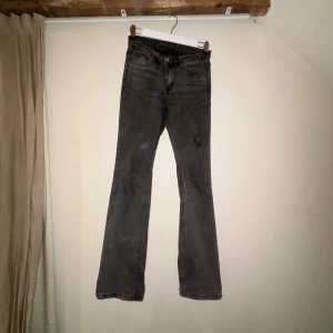 Grå bootcut jeans med råa kanter - Säljer ett par grå jeans med bootcut-modell och råa, slitna kanter nertill. Jeansen har klassisk femficksdesign och en liten sliten detalj på ena benet. Perfekta för dig som gillar en avslappnad och trendig look. Säljer då dom blivit förstora för mig över låren, dom är mycket strechiga. Använd mycket.