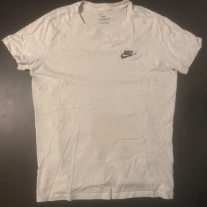 Vit Nike t-shirt S - Klassisk vit t-shirt från Nike med svart broderad logga på bröstet.