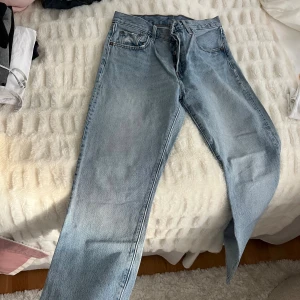 Levi's 517 ljusblå bootcut jeans - Ljusblå Levi's 517 jeans med klassisk bootcut passform och femficksdesign. Jeansen har hög midja, knappgylf och tydliga Levi's-detaljer som läderpatch och röd etikett bak. Tillverkade i robust denim för en tidlös look.