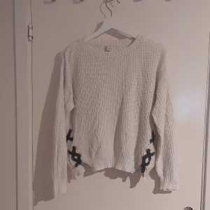 Vit stickad tröja UNIQ Young - Vit stickad tröja från UNIQ Young i storlek 146/152 mrn passar xxs/xs (enligt mig). Tröjan har coola mörkblå snörningsdetaljer i sidorna.. Perfekt för dig som gillar en unik och trendig look.