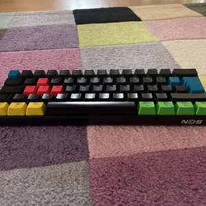 NOS C450 Mini Keyboard - NOS C450 Mini Keyboard i mycket fint skick. Kompakt design med färgglada keycaps för gaming och produktivitet. Mekaniska brytare ger snabb respons. Inga synliga defekter eller slitage. Perfekt för dig som vill ha ett smidigt och stilrent tangentbord till datorn.