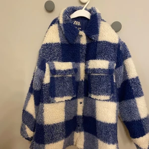 Blåvit teddyjacka i rutig fleece Zara - Supermysig teddyjacka från Zara i blåvitt rutigt mönster. Jackan har två stora bröstfickor med lock, klassisk krage och är gjord i fluffig fleece. Perfekt för dig som vill sticka ut med en cool och trendig look. Pris kan diskuteras 💙
