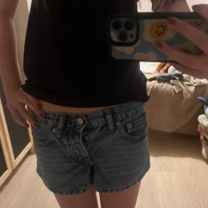 Blå jeansshorts med broderade fickor - Snygga blå jeansshorts från 157 med låg midja och klassisk femficksdesign. Baksidan har coolt mörkblått broderi på båda bakfickorna. Shortsen är i ett tvättat denimtyg och har knapp och dragkedja framtill. Perfekta för sommarens alla häng!