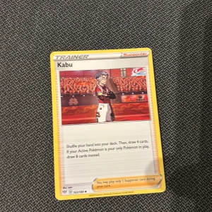 Kabu - Cool supporter-kort från Pokémon TCG! Kabu står i arenan redo för strid. Perfekt för dig som vill boosta din samling eller förbättra ditt spel. Kortet har snygg design och är ett måste för alla Pokémon-fans.