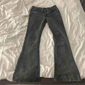 Svarta bootcut jeans från Gina Tricot  - Snygga svarta bootcut jeans från Gina tricot i storlek 36. Jeansen har klassisk femficksdesign, hög midja och vida ben med råa kanter nertill. Materialet är jeans i bomullsmix och färgen är tvättad svart med lite slitningar för en cool look.