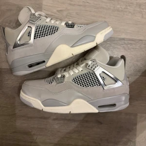 Nike Jordan 4 Retro Metallic Silver - Säljer ett par Nike Jordan 4 Retro sneakers i grått och silver med coola metallicdetaljer. Skorna har meshpaneler, snörning och en platt sula med Air-enhet. Materialmix av mocka och syntet, med ikonisk Jumpman-logga under sulan. Perfekt för dig som gillar stilrena och moderna sneakers.