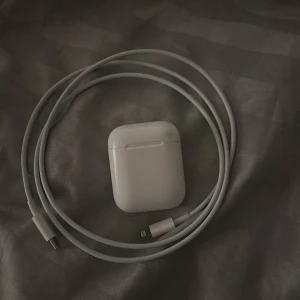 AirPods (2nd generation) med laddningsetui - Säljer ett par Apple AirPods (2nd gen) med original laddningsetui och Lightning-laddkabel. Fungerar utmärkt, mindre repor och lätt smuts på etuiet men inget som påverkar funktionen. Perfekt för trådlös musik och samtal.
