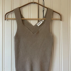 Beige glitter topp  - Säljer en beige ribbad linnetopp från Kappahl i storlek XS. Toppen har v-ringning och är glittrig