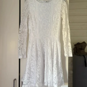 Vit spetsklänning  - Superfin vit kortklänning i spets från Cubus. Klänningen har långärmade ärmar, rund halsringning och dragkedja i ryggen. Ärmarna är i nedbragt spets. Den är helfodrad och har ett vackert blommigt spetsmönster som ger en romantisk vibe. Perfekt för sommarens alla tillfällen!