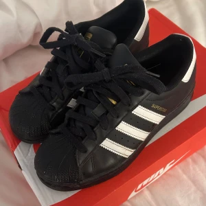 Svarta Adidas Superstar sneakers - Säljer mina Adidas Superstar sneakers i svart då dem inte kommer till användning,  gåtts med fåtal gånger .