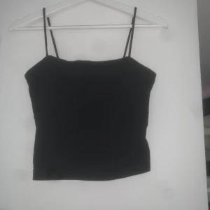Svart linne - Enkel och stilrent svart linne från Gina Tricot med tunna axelband. Toppen har rak skärning och är tillverkad i mjuk bomullsmix som känns skön mot huden. 